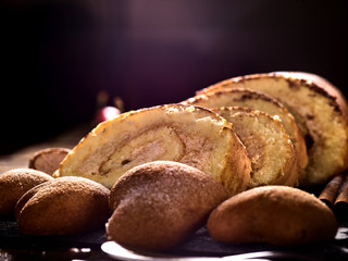Sand cookies heart shape , rolled cake with cream and cinnamon stick, on kitchen on table in village style at morning sun flare.