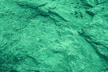 Vintage green background. Rough painted wall of emerald color. Imperfect plane of virid colored. Uneven old decorative toned backdrop of green tint. Texture of emerald hue. Ornamental stony surface.