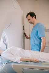 handsome attentive radiologist operating mri machine during patients diagnostics