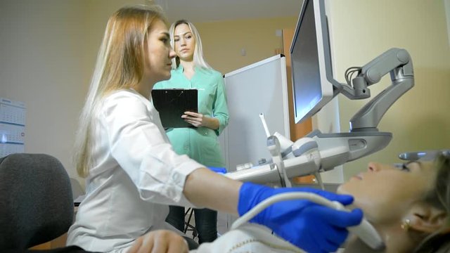 Doctor Taking A Sonogram Thyroid gland, nurse writes and helps the doctor. Camera slide