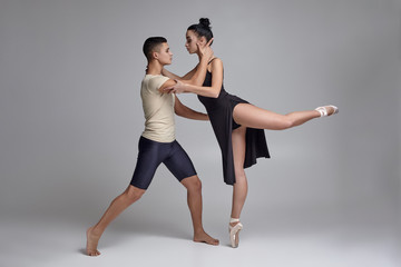 Two athletic modern ballet dancers are posing against a gray studio background.