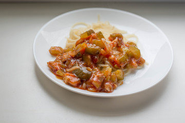 Macaroni with vegetables and meat on a white plate