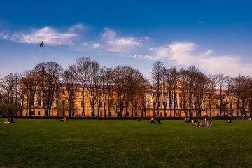 Obraz premium People rest on the meadow of the Alexander Garden with the Admiralty Building in the background at dawn in Saint Petersburg, Russia