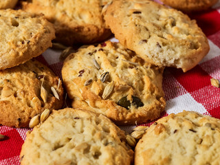 Oatmeal cookies with husk whole oats on red kitchen gingham checkered cotton fabric on table in farm-style.
