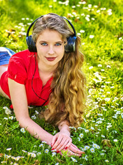 Girl in headphones catch rhythm music on green grass with chamomile flowers summer outdoor. Walking...