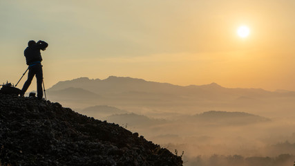 Fototapeta premium sunrise views in the summer that emerge from the hills in a village with photographer sillhouette