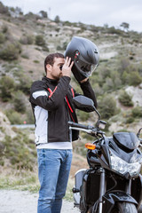 Fototapeta na wymiar Young male biker putting on his helmet to drive his motorbike