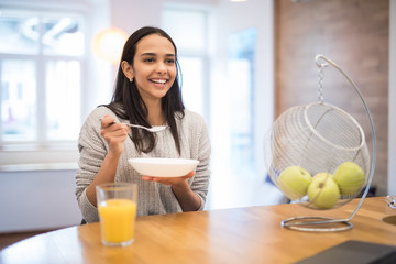 Portrait of beautiful pretty young woman having breakfast in the kitchen.