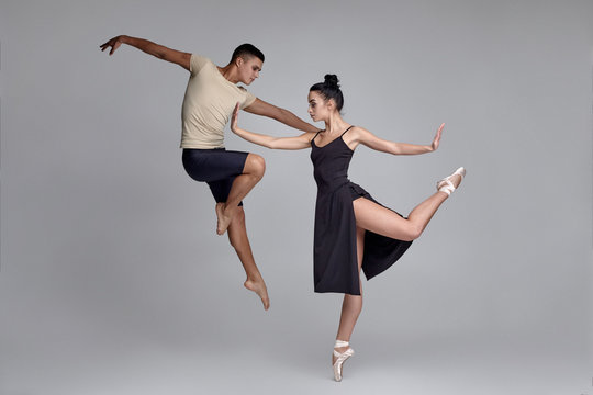 Two athletic modern ballet dancers are posing against a gray studio background. - Powered by Adobe