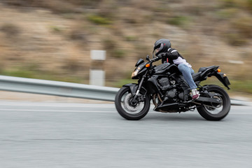 Obraz na płótnie Canvas Biker driving his black motorbike by road