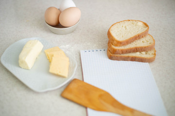 We cook a great breakfast. In the photo: sauces, flour, olive oil, wheat, butter, cheese, bread and a notebook.