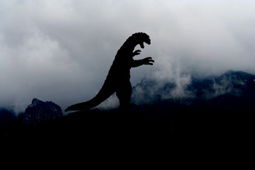 Godzilla-artiges Monster als schwarze Silhouette auf einem Berg