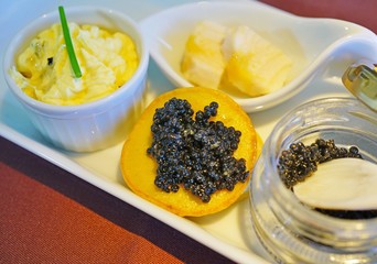 Expensive gourmet black sturgeon caviar fish roe with blinis and a mother-of-pearl spoon