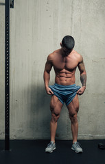 Young strong man posing and flexing his quadriceps legs muscles