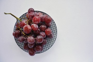 Ripe red grape in a plate. Pink bunch isolated on white background, top view