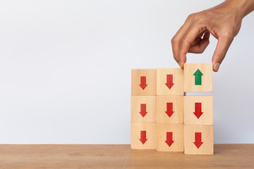 Hand arranging wooden cube stack with arrows pointing up on white background. Concept of growth and success or rising successful development and business development in the future