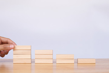 Hand arranging wooden cube stack a staircase on white background. Concept of success, winner, victory or top ranking