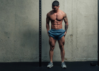 Young strong man posing and flexing his quadriceps legs muscles