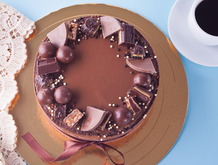 Chocolate cake with candy and ribbon on a blue table