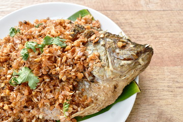batter fried mango fish topping chop garlic on banana leaf