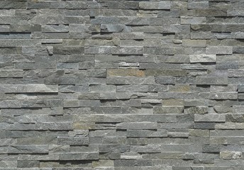 Stone wall cladding made of horizontal gray shades strips of rock . Background and texture
