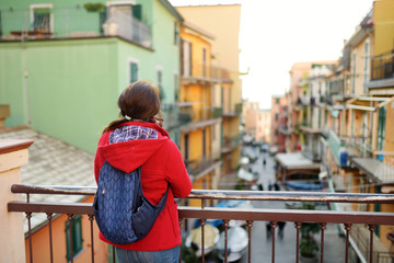 Young female tourist enjoying the view of Manarola, one of the five centuries-old villages of Cinque Terre, located on rugged northwest coast of Italian Riviera, Italy.