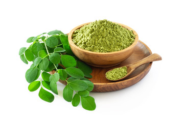 Moringa powder in wooden bowl with original fresh Moringa leaves isolated on white background.