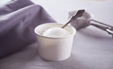 Paper bowl with ice cream with gray napkin and on a gray table