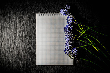 A notepad with field flowers on a black background