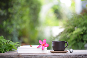 Black coffee cup with flower and notebook at outdoor