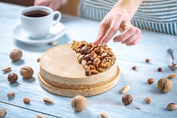 Raw nutty cake decorated with walnut, almond, hazelnut on a blue wooden background. Gluten free and sugar free food