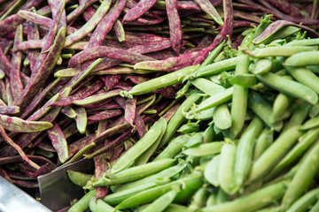 green and purple beans for sale on a shelf in the central market