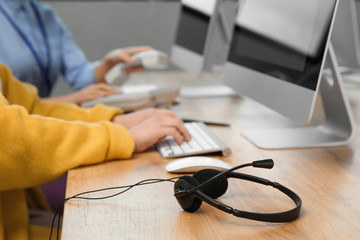 Technical support operators working at table in office, focus on headset