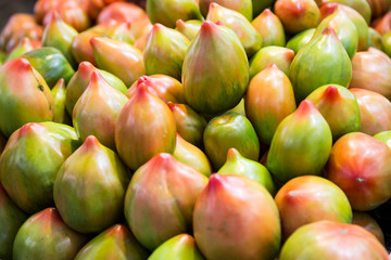 Red and green tomatoes showing on a shelf of the central market