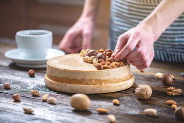 Raw nutty cake decorated with walnut, almond, hazelnut on a dark wooden background. Gluten free and sugar free food