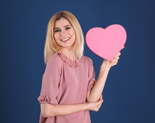 Beautiful woman with heart shaped box on color background