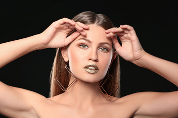 Naklejka premium Portrait of beautiful lady with gold lipstick on black background