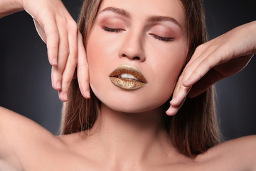 Fototapeta premium Woman with gold lipstick on grey background, closeup