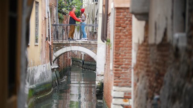 Italy, Venice. A young couple standing on the bridge above a water channel