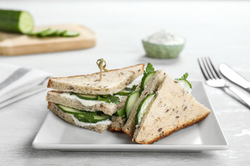 Plate with tasty cucumber sandwiches served on table