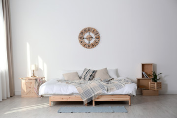 Bed with pillows and plaid in modern room interior