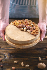 Raw nutty cake decorated with walnut, almond, hazelnut on a dark wooden background. Healthy fresh vegan dessert.