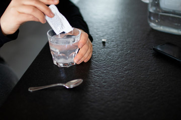 Woman dissolves medicine with soluble sachet in a water. Soluble powder drug dissolved in water, self-medication  without a prescription for headache, toothache and pain. Pain medication