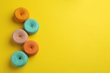 Clews of knitting threads on color background, flat lay with space for text. Sewing stuff