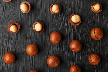 Purified and shell repeats macadamia nuts on black textural stone background. Healthy eating concept
