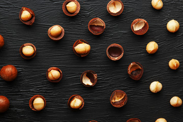 Purified and shell repeats macadamia nuts on black textural stone background. Healthy eating concept