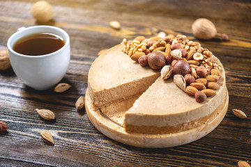 Raw nutty cake decorated with walnut, almond, hazelnut on a dark wooden background. Gluten free and sugar free product