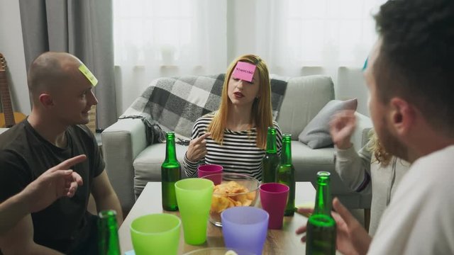 In the living room friends playing Who am I game with sticky papers on head