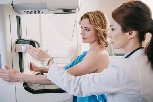 attentive radiographer adjusting x-ray machine for mammography test while standing near patient