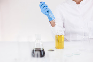 Scientist working with pharmaceutical cbd oil in a laboratory with glass dropper and a bowl